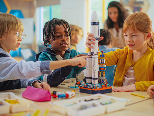 Drei Kinder bauen eine Weltraumrakete. Foto: shutterstock.com / Gorodenkoff