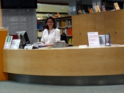 Bibliothekarin sitzt an der Infotheke