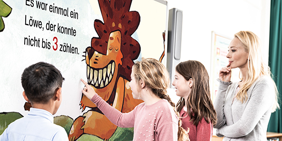 Drei Kinder und eine Erwachsene vor einem Bilderbuchkino auf einem Whiteboard