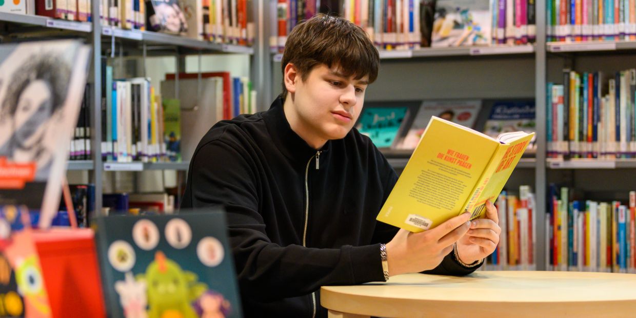 Jugendlicher liest in der Stadtbibliothek